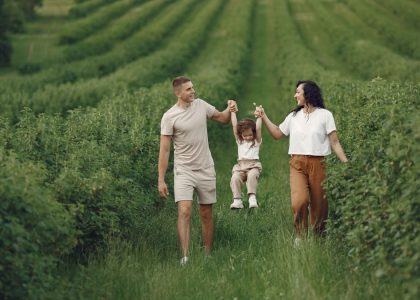 A happy family walking in a lush, green rural field together.